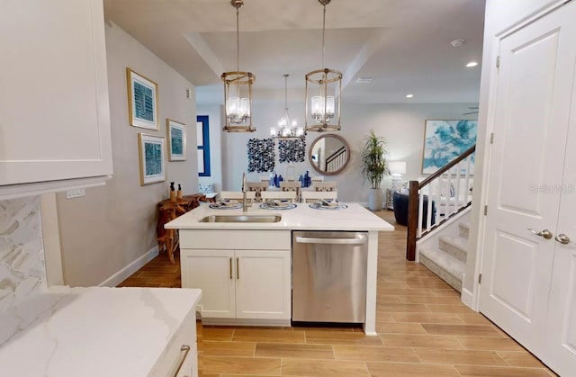 kitchen featuring stainless steel dishwasher, sink, pendant lighting, white cabinets, and light hardwood / wood-style floors