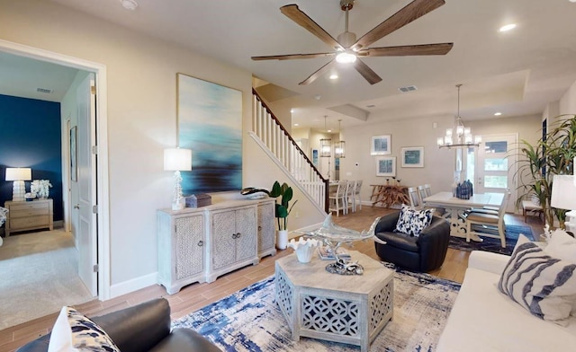 living room featuring light wood-type flooring and ceiling fan with notable chandelier