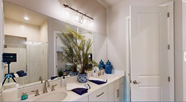 bathroom featuring a shower with door and vanity