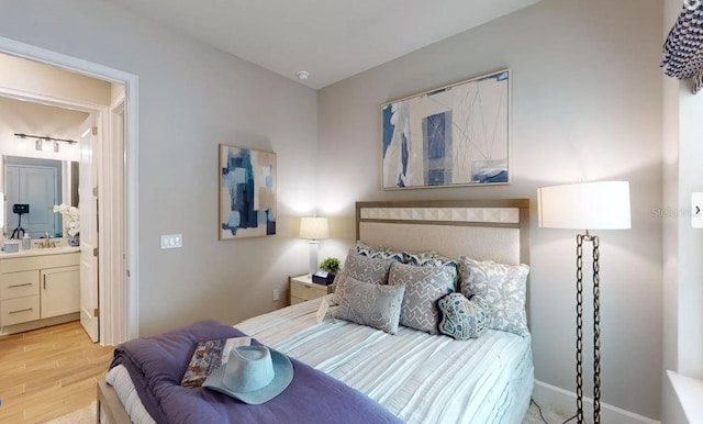 bedroom with light hardwood / wood-style floors, ensuite bath, and sink