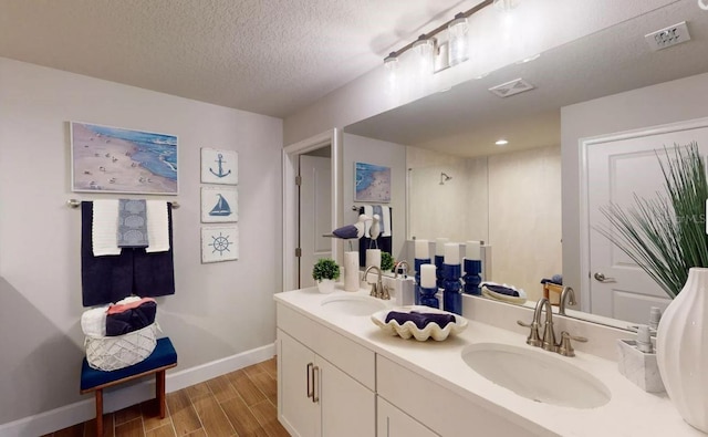 bathroom with hardwood / wood-style floors, vanity, and a textured ceiling