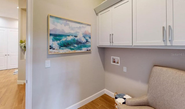 clothes washing area featuring cabinets, hookup for a washing machine, and light hardwood / wood-style floors