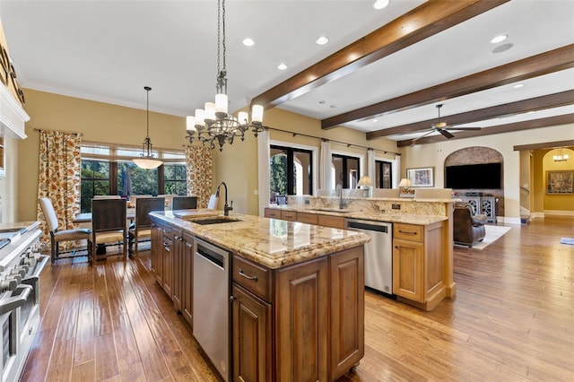 kitchen with hanging light fixtures, light stone countertops, stainless steel appliances, and a large island with sink