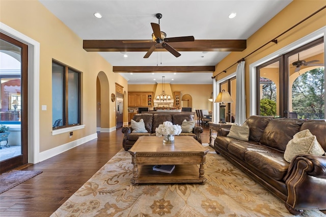 living room featuring beamed ceiling, ceiling fan with notable chandelier, and hardwood / wood-style flooring