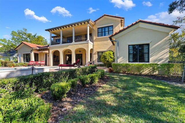 mediterranean / spanish house with a front yard, a balcony, and a patio area