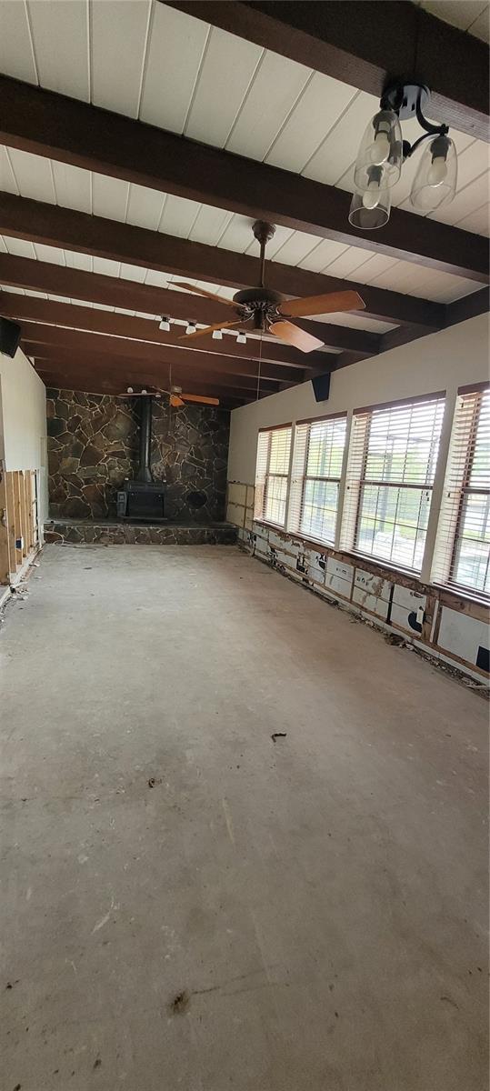 interior space with a wood stove and ceiling fan