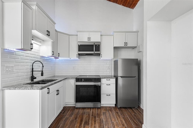 kitchen with sink, vaulted ceiling, dark hardwood / wood-style flooring, white cabinetry, and stainless steel appliances