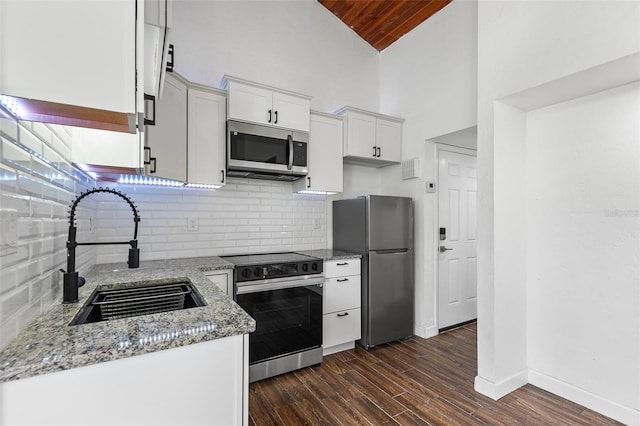 kitchen with light stone countertops, stainless steel appliances, sink, wooden ceiling, and white cabinetry