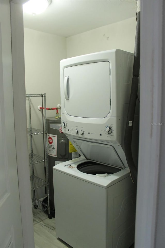 laundry area with water heater and stacked washer and dryer