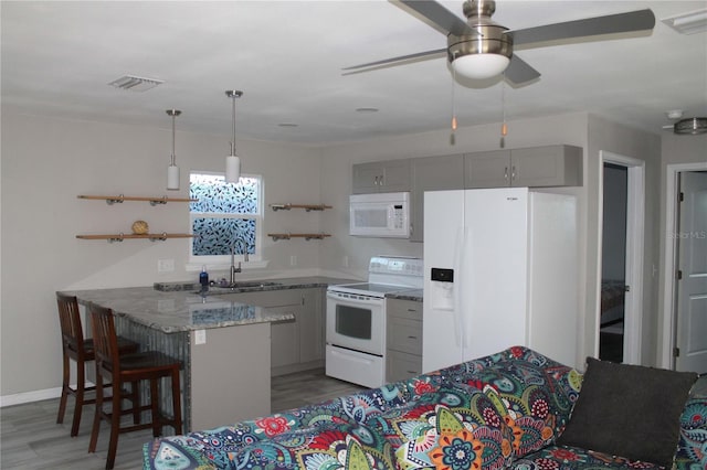 kitchen featuring kitchen peninsula, light stone countertops, gray cabinetry, white appliances, and sink