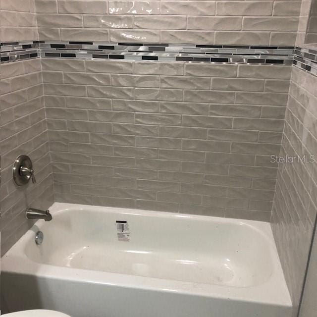 bathroom with tiled shower / bath combo and toilet