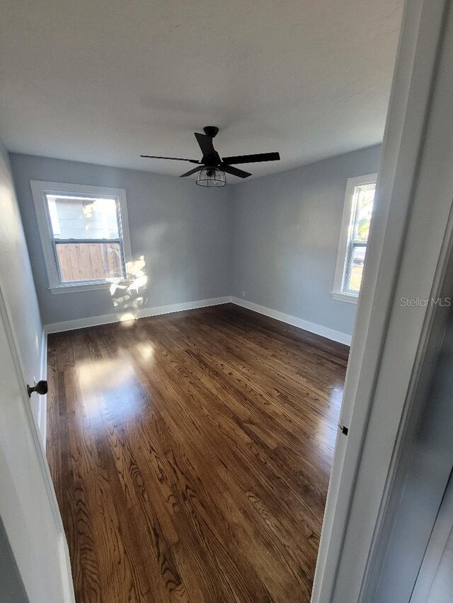 unfurnished room with ceiling fan and dark wood-type flooring