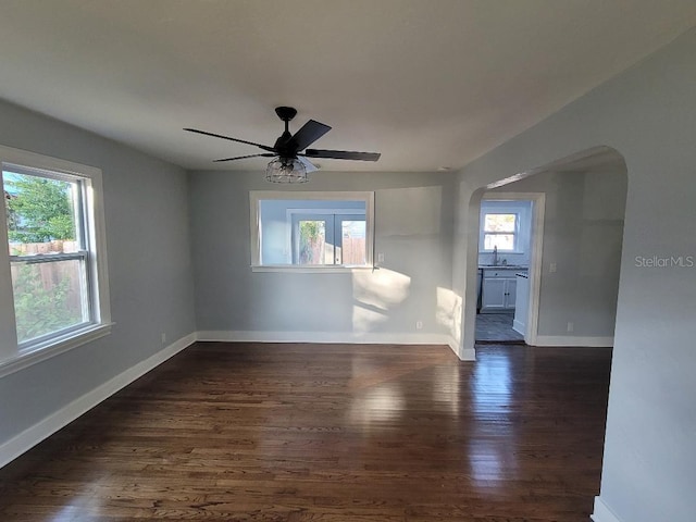 unfurnished room featuring dark wood-type flooring, ceiling fan, and a healthy amount of sunlight