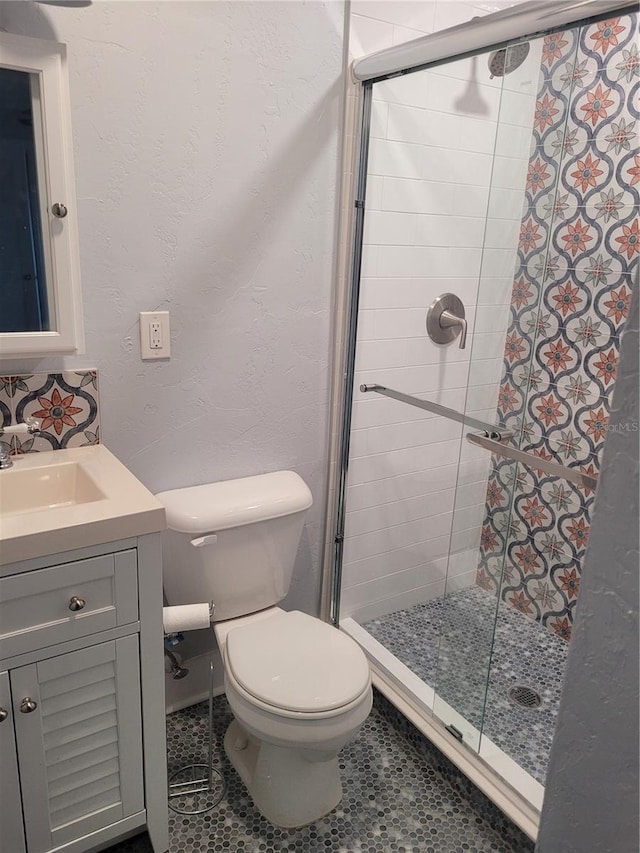 bathroom featuring vanity, a shower with shower door, and toilet