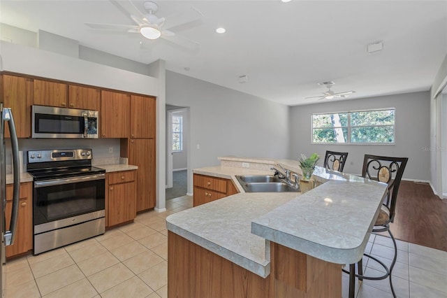 kitchen featuring appliances with stainless steel finishes, a kitchen breakfast bar, sink, light tile patterned floors, and an island with sink