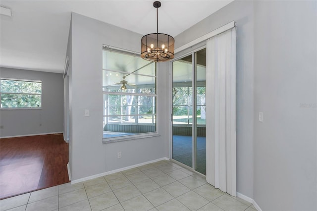 unfurnished dining area featuring ceiling fan with notable chandelier and light hardwood / wood-style floors