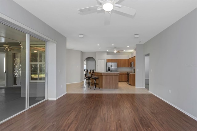 kitchen with a kitchen bar, stainless steel appliances, light hardwood / wood-style flooring, and a kitchen island