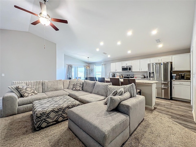 living room featuring ceiling fan, hardwood / wood-style floors, lofted ceiling, and sink