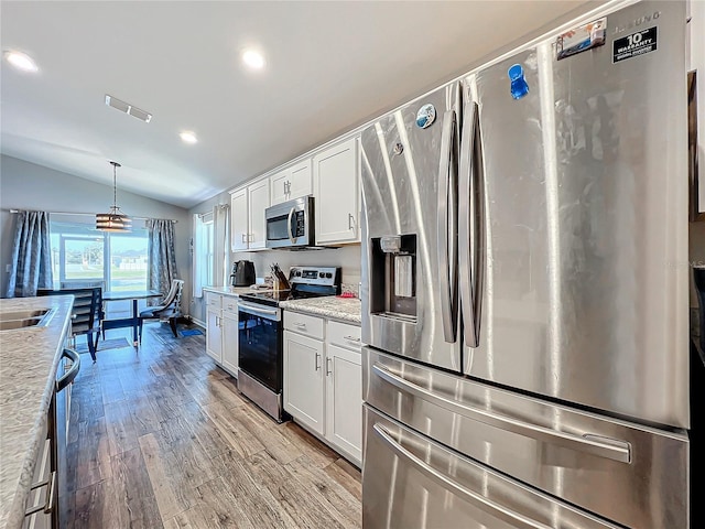 kitchen with white cabinets, appliances with stainless steel finishes, light hardwood / wood-style flooring, and lofted ceiling