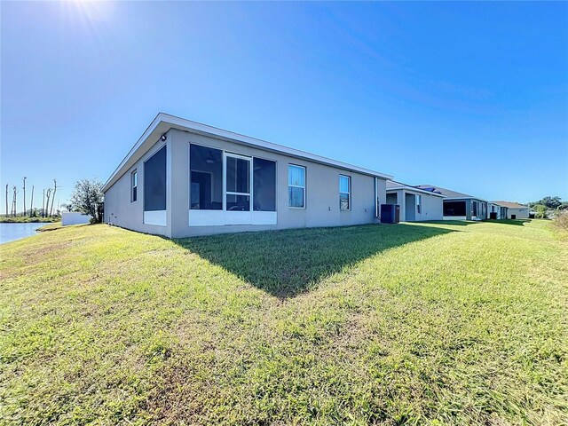 back of house featuring central AC, a yard, and a water view