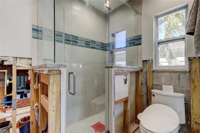 bathroom featuring a shower with door, tile walls, and toilet