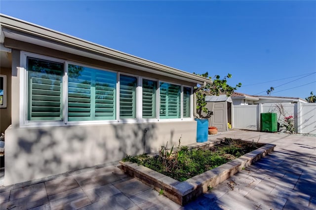 view of side of property with a patio and a storage unit