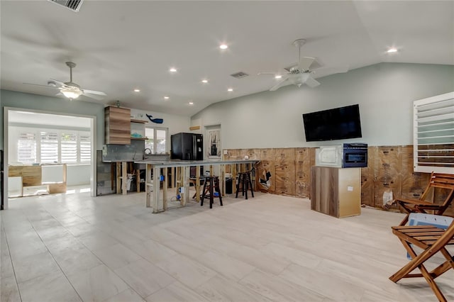 interior space with ceiling fan, wooden walls, and vaulted ceiling