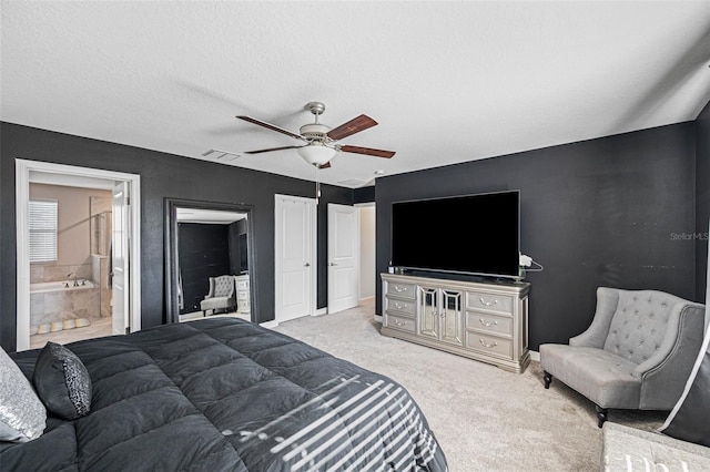 carpeted bedroom with a textured ceiling, connected bathroom, and ceiling fan