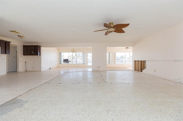 unfurnished living room featuring ceiling fan with notable chandelier