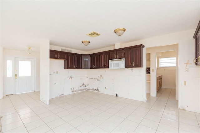 kitchen featuring dark brown cabinetry, a wealth of natural light, and light tile patterned floors