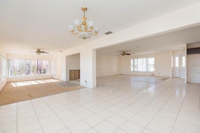 tiled spare room with ceiling fan with notable chandelier and a wealth of natural light