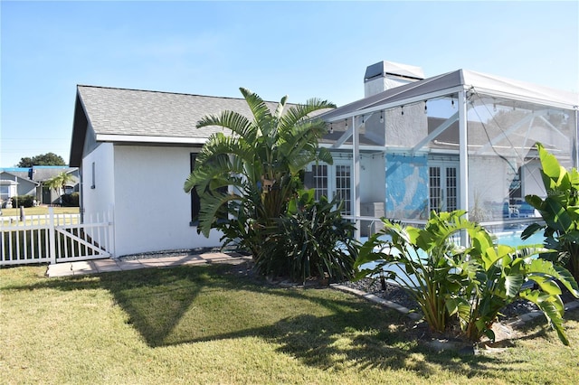 view of side of property with a yard and glass enclosure