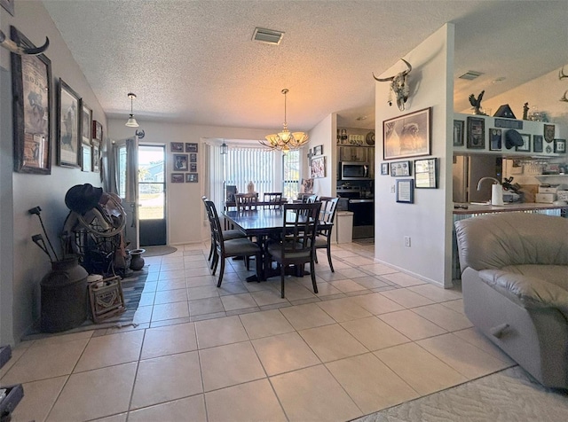 tiled dining room with a chandelier and a textured ceiling