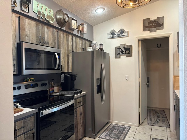 kitchen with appliances with stainless steel finishes, a textured ceiling, and light tile patterned floors