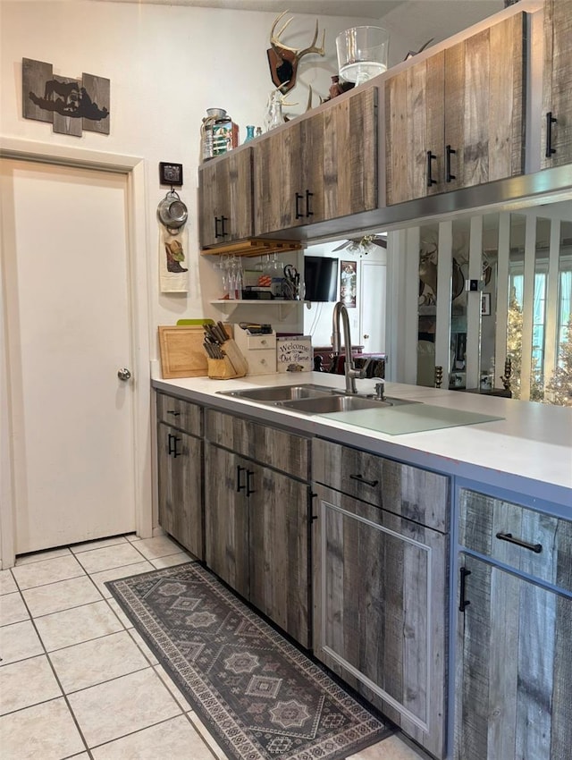 kitchen with dark brown cabinets, sink, and light tile patterned flooring