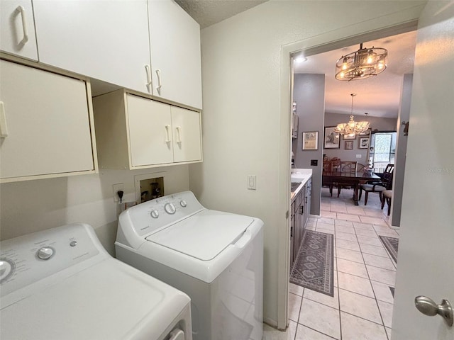 laundry area featuring cabinets, independent washer and dryer, a textured ceiling, light tile patterned floors, and a chandelier