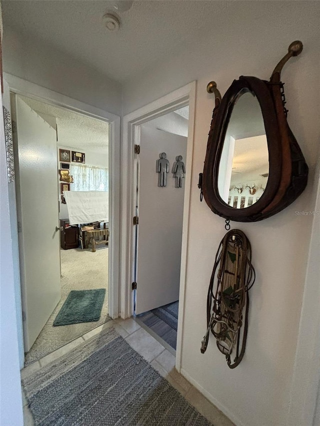 corridor with light tile patterned floors and a textured ceiling