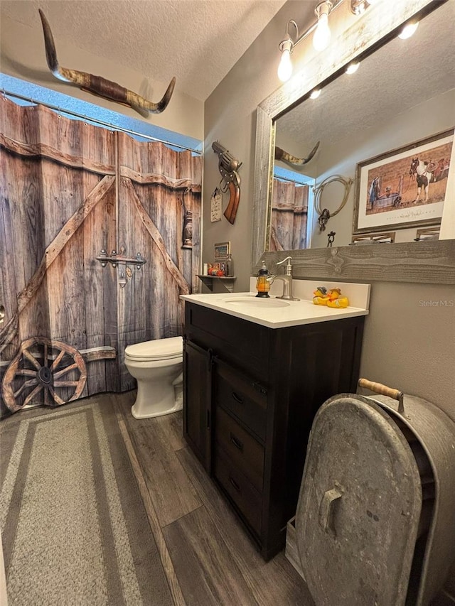 bathroom featuring a shower with curtain, a textured ceiling, toilet, vanity, and hardwood / wood-style flooring