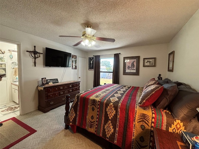 bedroom with light carpet, a textured ceiling, ensuite bath, and ceiling fan