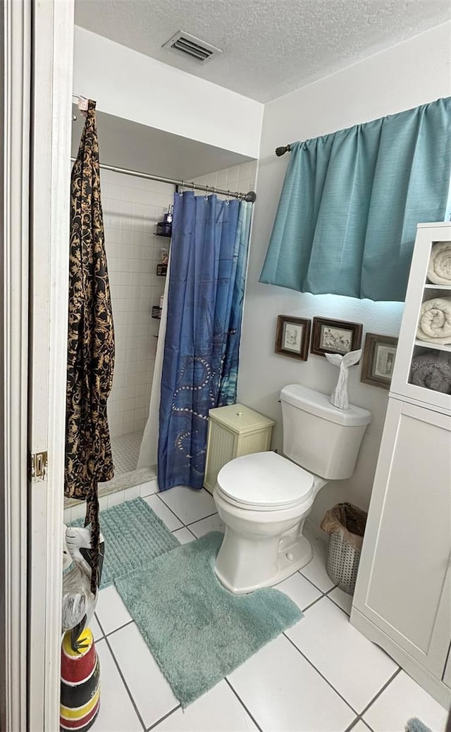 bathroom featuring toilet, a textured ceiling, tile patterned floors, and walk in shower