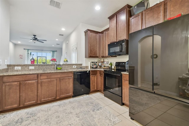 kitchen featuring black appliances, sink, ceiling fan, light stone countertops, and light tile patterned floors