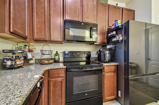 kitchen featuring black appliances, light stone counters, and light tile patterned floors