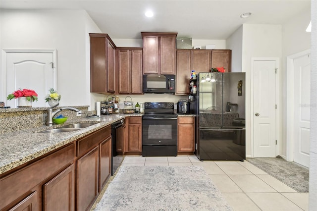 kitchen featuring light tile patterned floors, sink, light stone counters, and black appliances