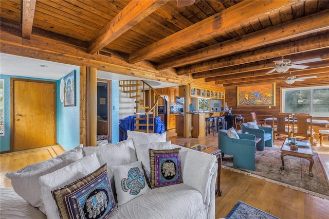 living room featuring beamed ceiling, wooden walls, light wood-type flooring, and wood ceiling