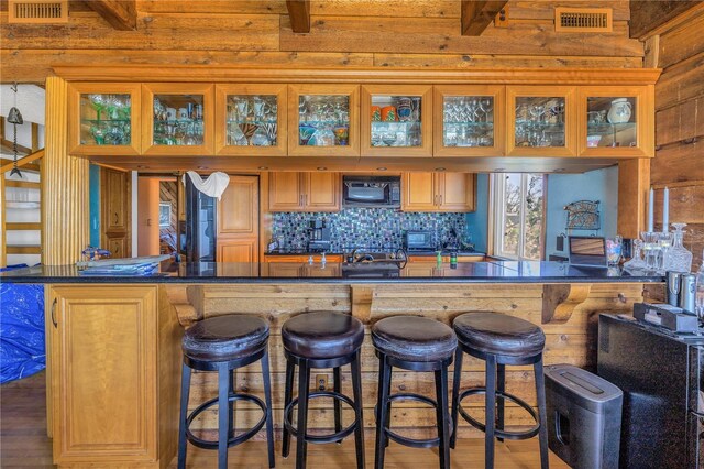 kitchen with beamed ceiling, a breakfast bar, and wood-type flooring