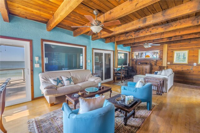 living room featuring wood walls, wooden ceiling, light hardwood / wood-style flooring, a wealth of natural light, and beamed ceiling