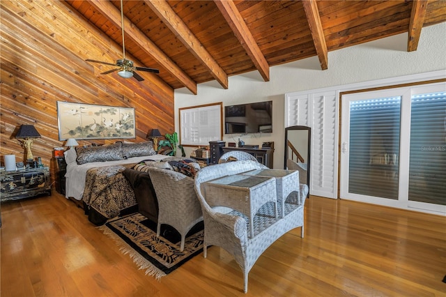 bedroom with wood walls, wooden ceiling, hardwood / wood-style flooring, ceiling fan, and beamed ceiling