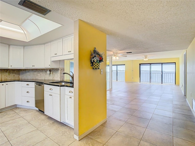 kitchen featuring sink, white cabinetry, light tile patterned floors, stainless steel dishwasher, and decorative backsplash