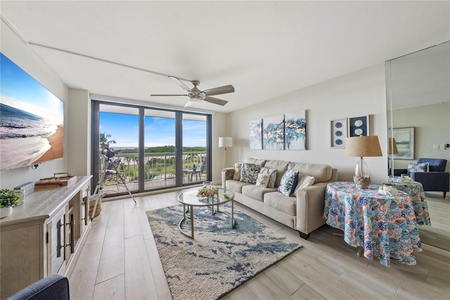 living room with ceiling fan, expansive windows, and light wood-type flooring