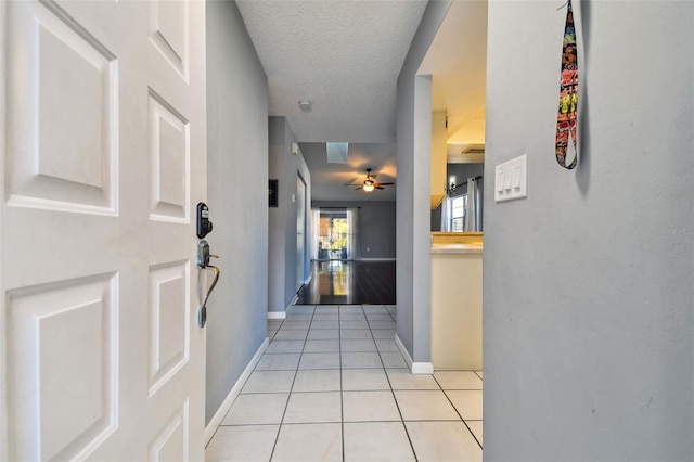 corridor featuring light tile patterned floors and a textured ceiling